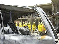 Saudi officials are seen through the charred wreckage of a car at the al-Hamra compound