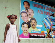 A Cuban girl stands by a mural depicting five men imprisoned in the United States as spies.