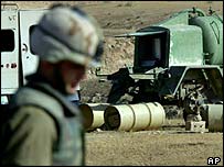 A US soldier looks at suspicious drums of liquid in Iraq